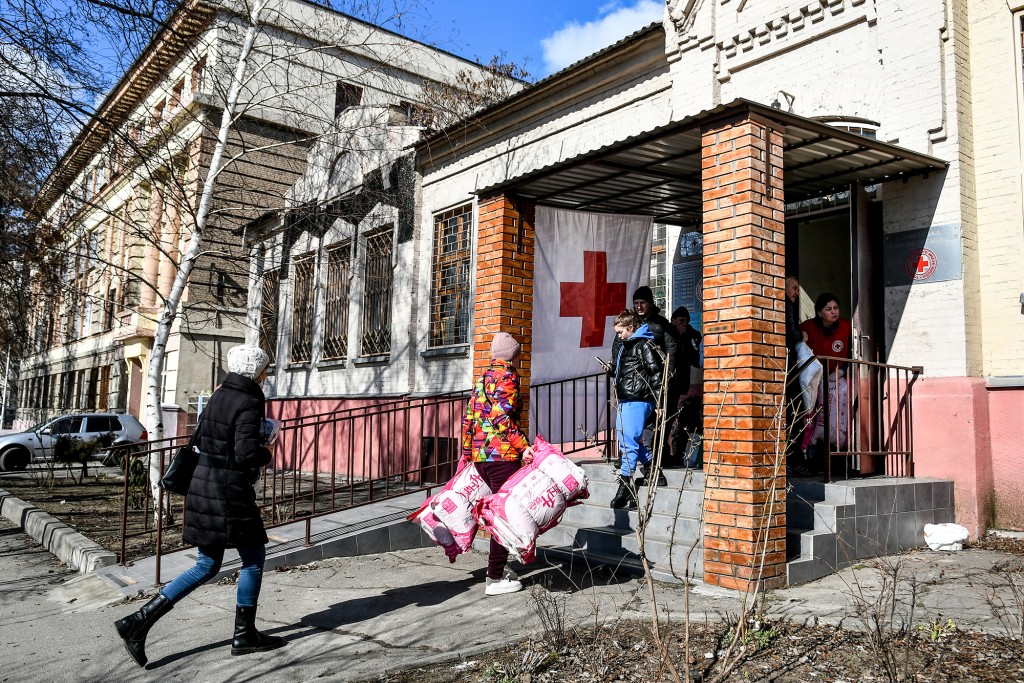 Voluntários carregando suprimentos entram em um local da Cruz Vermelha na Ucrânia