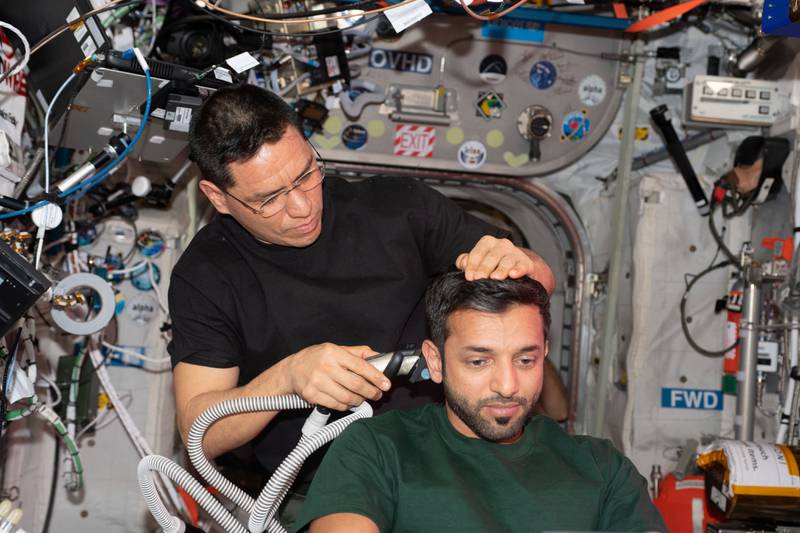 O astronauta da NASA Frank Rubio corta o cabelo do astronauta dos Emirados Sultan Al Neyadi na Estação Espacial Internacional.  Foto: Centro Espacial Mohammed bin Rashid