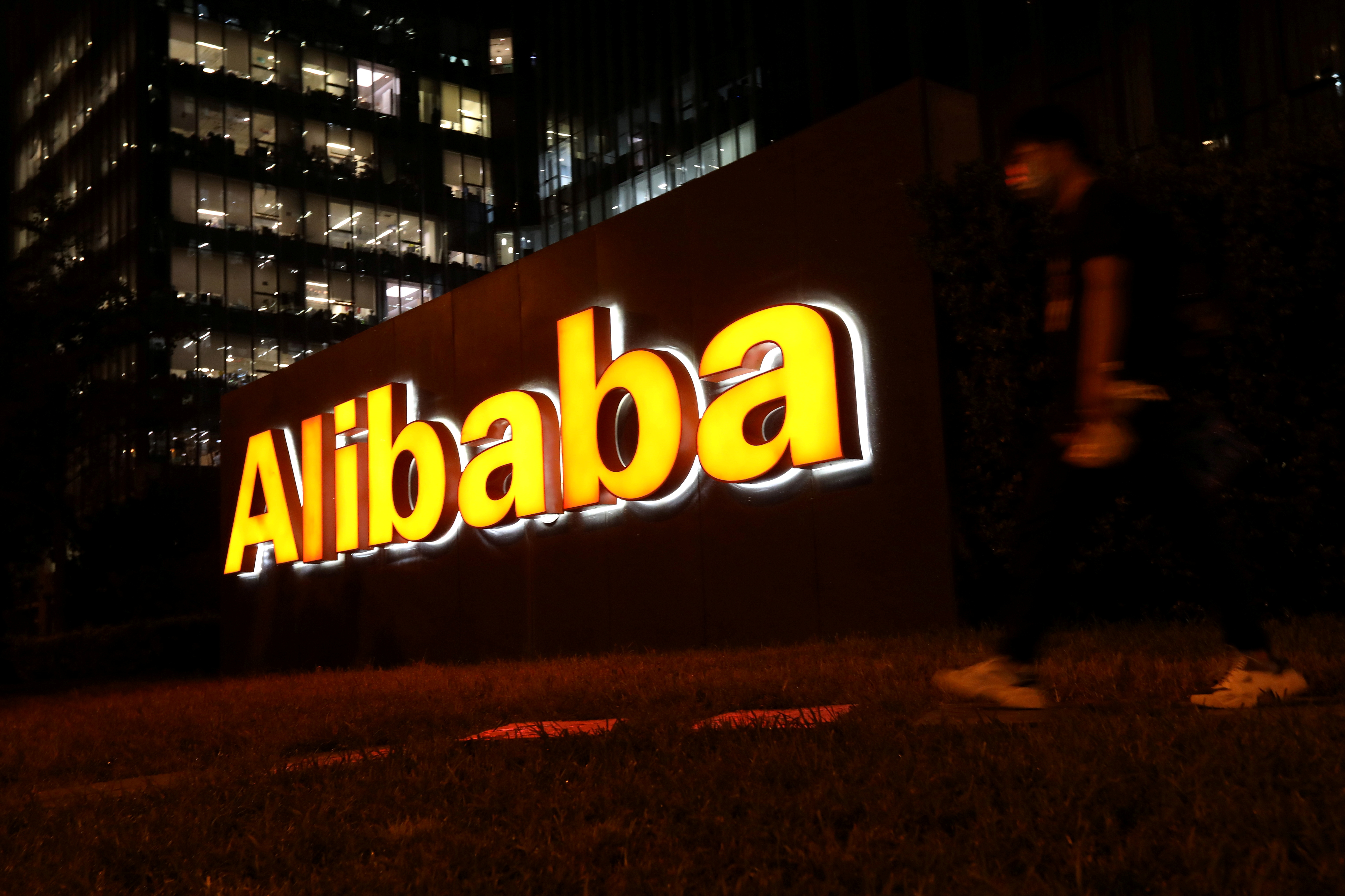 Um homem caminha perto do logotipo do Grupo Alibaba em seu prédio comercial em Pequim